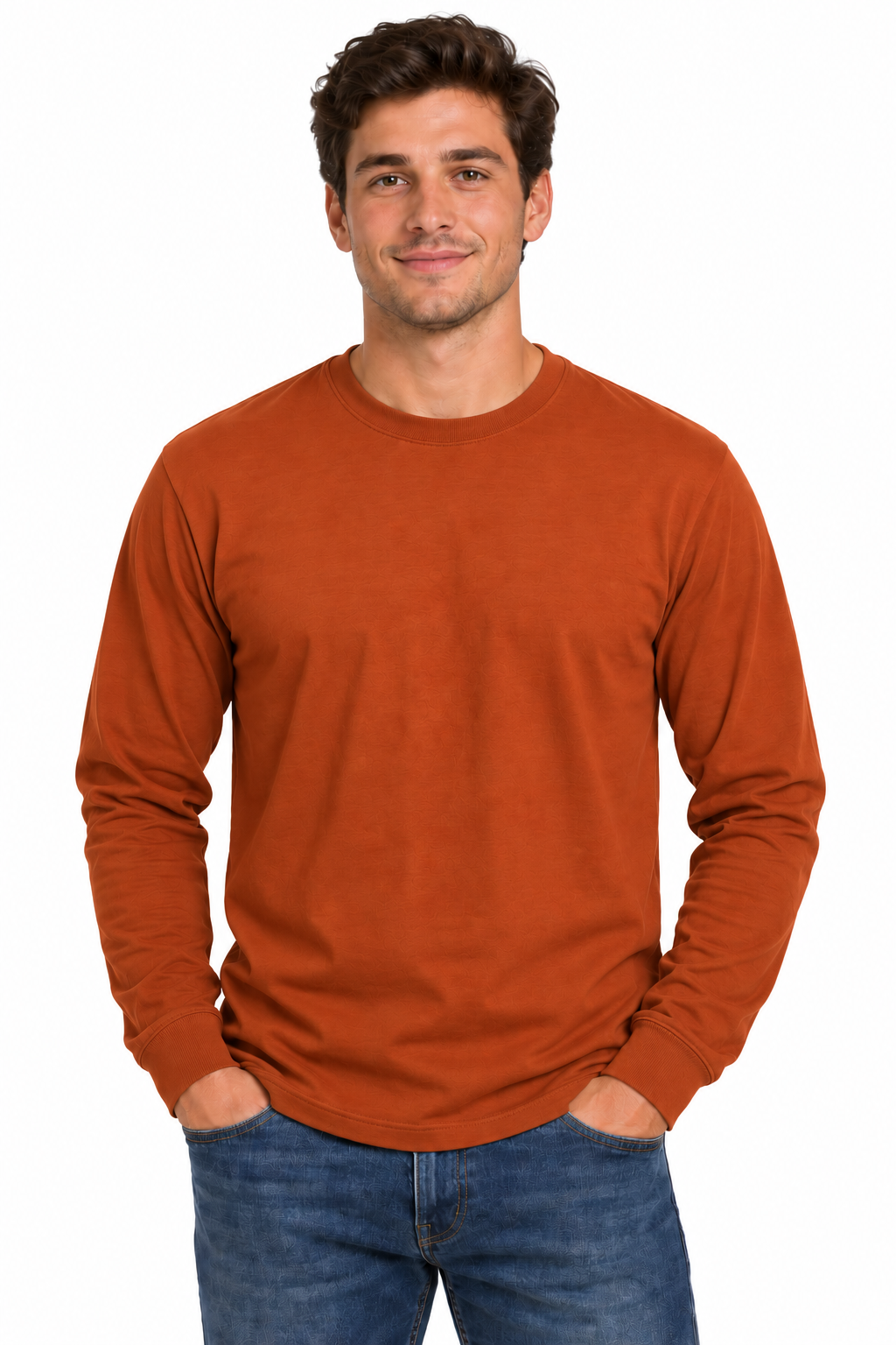 A man wearing a rust-orange long-sleeve crewneck t-shirt and blue jeans, standing against a plain white background.