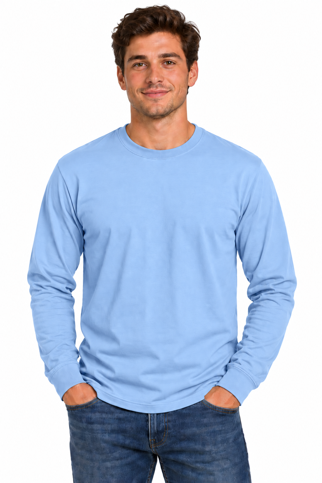 A man wearing a light blue long-sleeve crewneck t-shirt and blue jeans, standing against a plain white background.