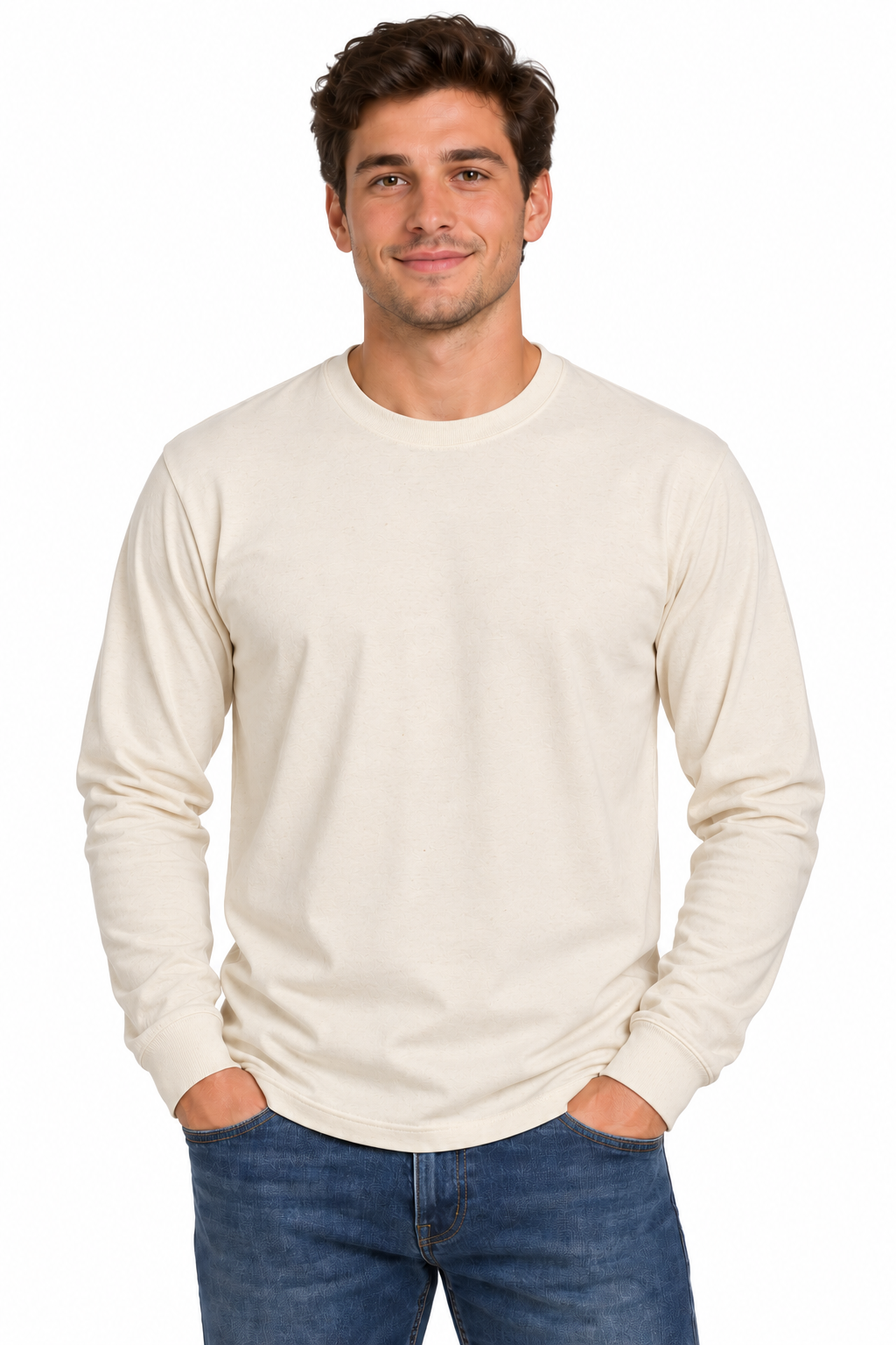 A man wearing a light cream-colored long-sleeve crewneck t-shirt and blue jeans, standing against a solid white background.