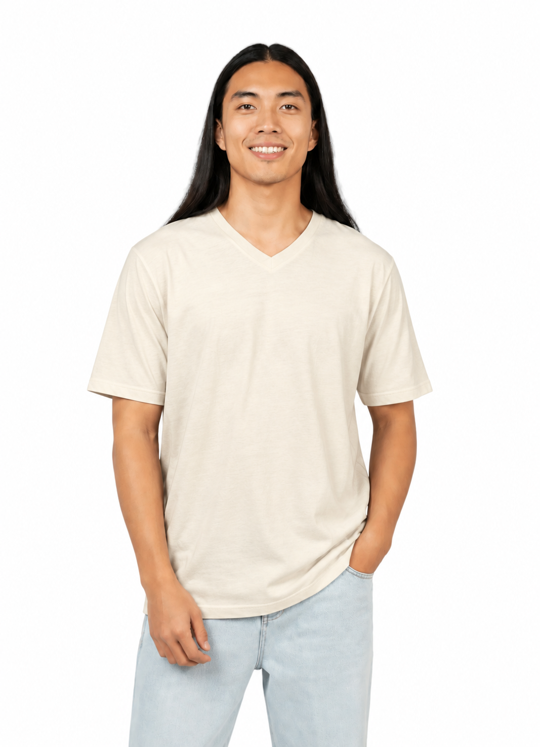 A smiling man with long black hair wearing a light beige short-sleeve v-neck t-shirt and light blue jeans, standing against a solid white background.