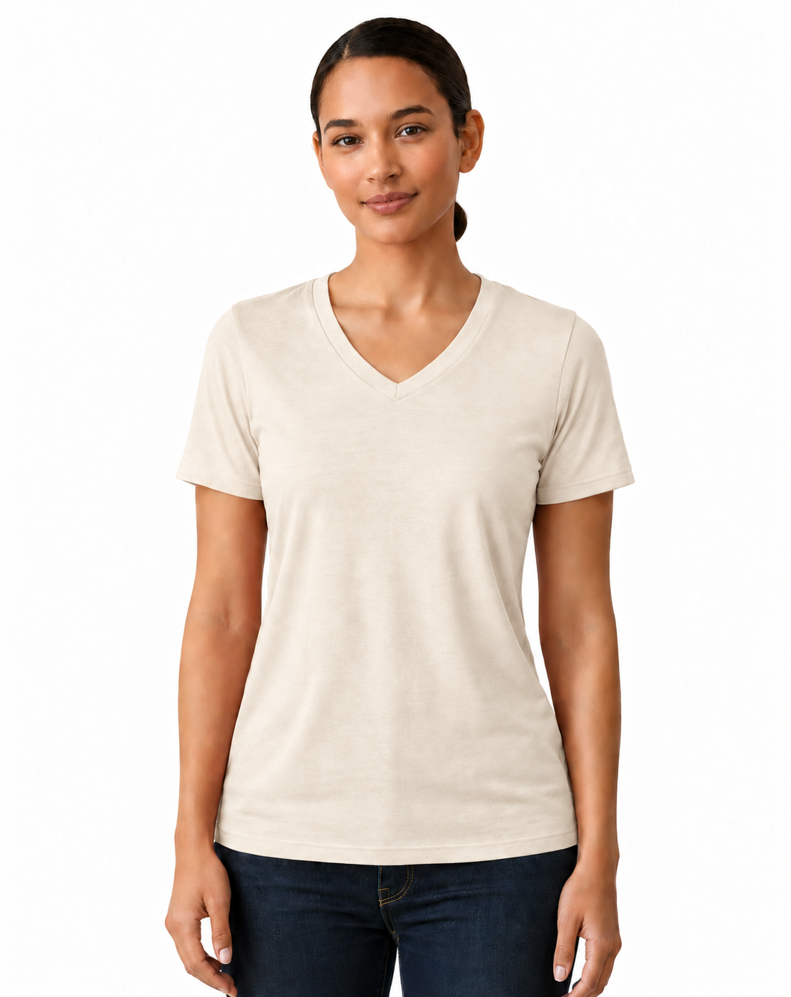 A woman modeling a short-sleeve V-neck t-shirt in a light cream color, paired with dark blue jeans, against a plain white background.
