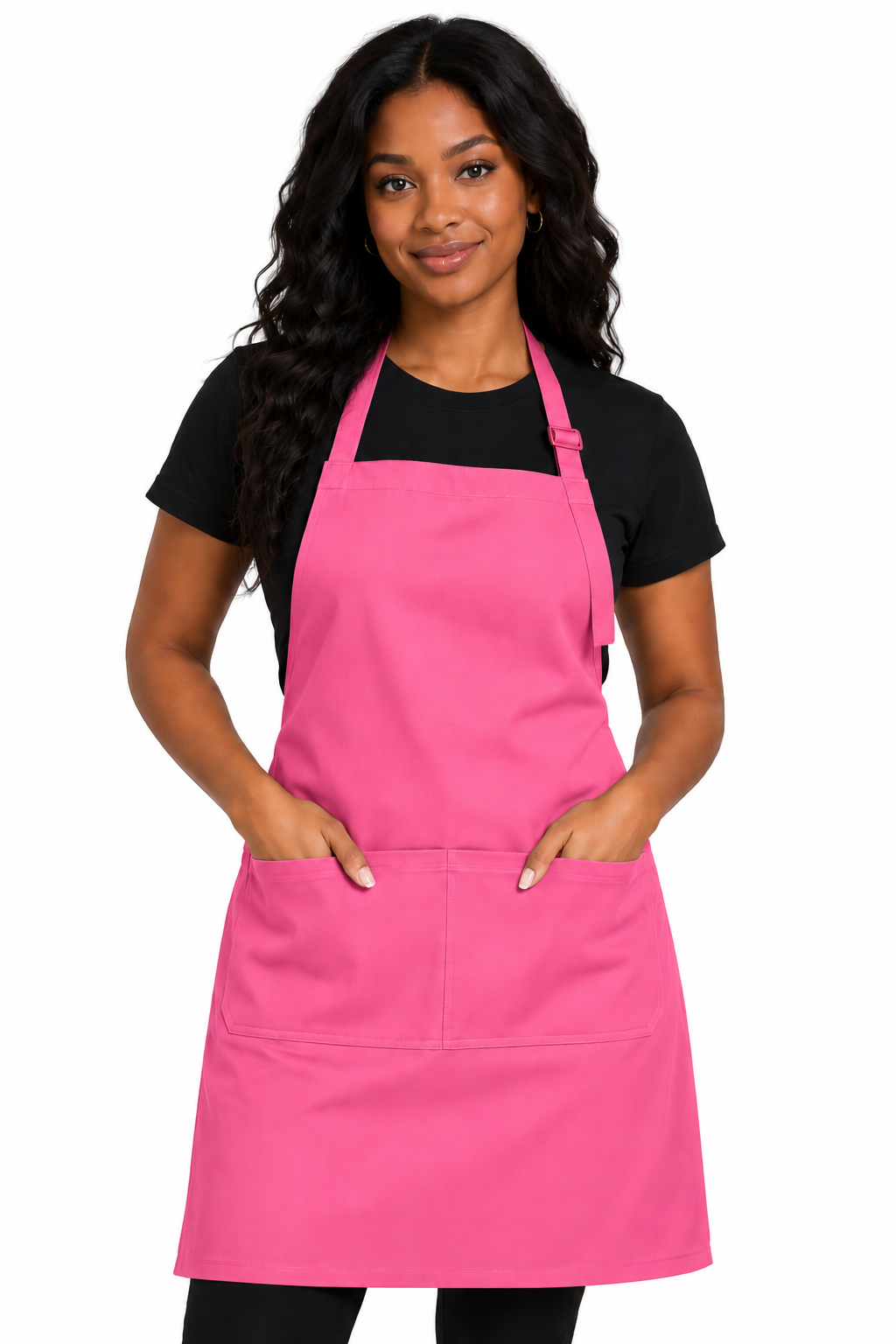 A woman modeling a bright pink kitchen apron with two front pockets over a black t-shirt, set against a plain white background.