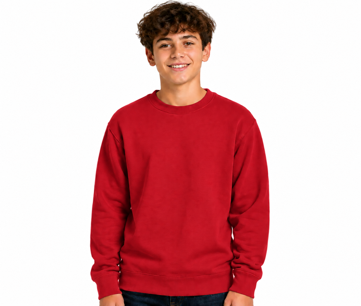 A smiling young man with curly brown hair wearing a solid red crewneck sweatshirt and dark blue jeans, standing against a plain white background.