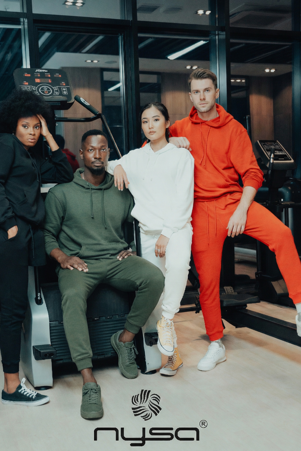 Four people posing together in a gym with 'nysa' branding.