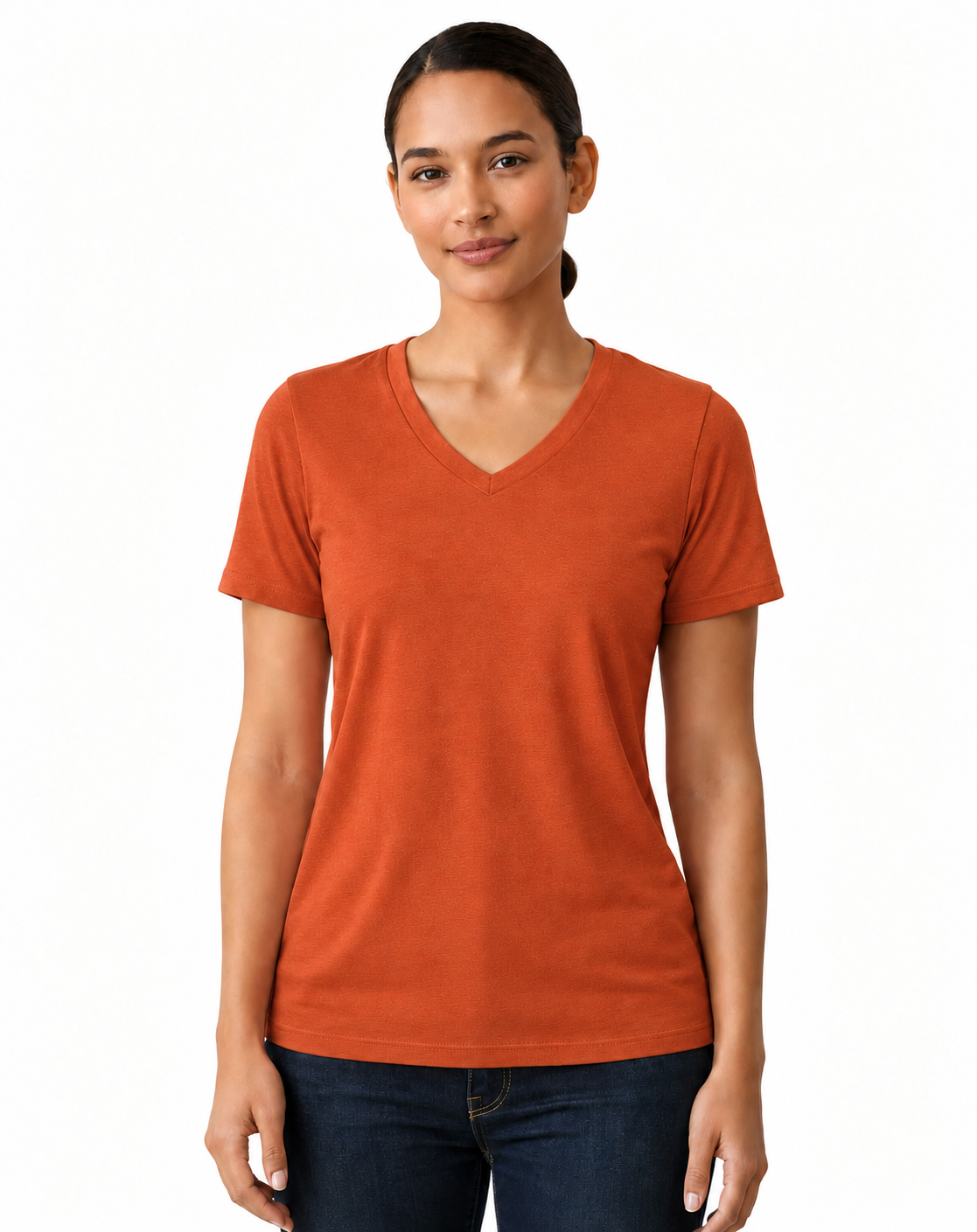 A woman modeling a short-sleeve V-neck t-shirt in a solid burnt orange color, paired with dark blue jeans, against a plain white studio background.