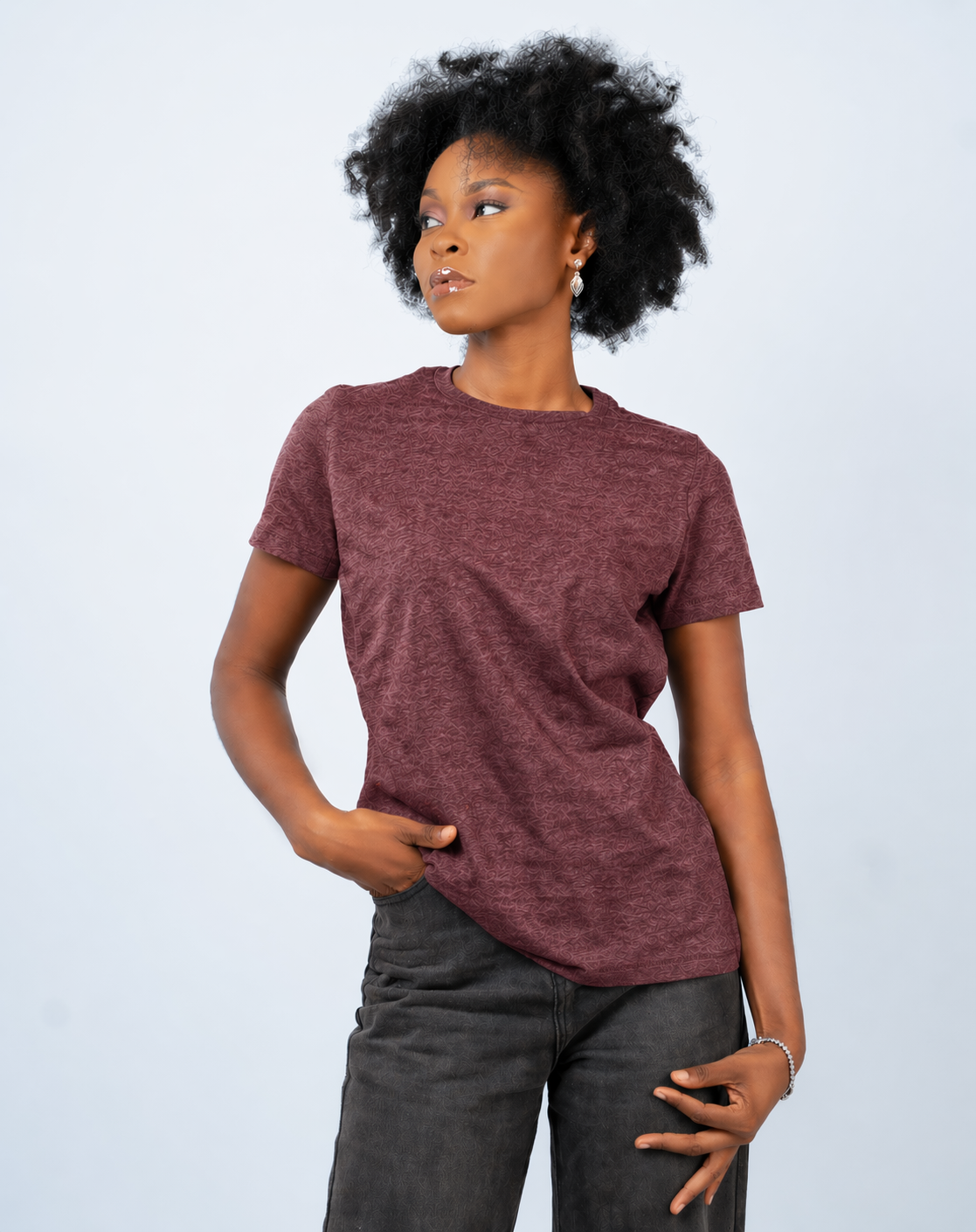 Person wearing a maroon t-shirt and dark pants on a light gray background