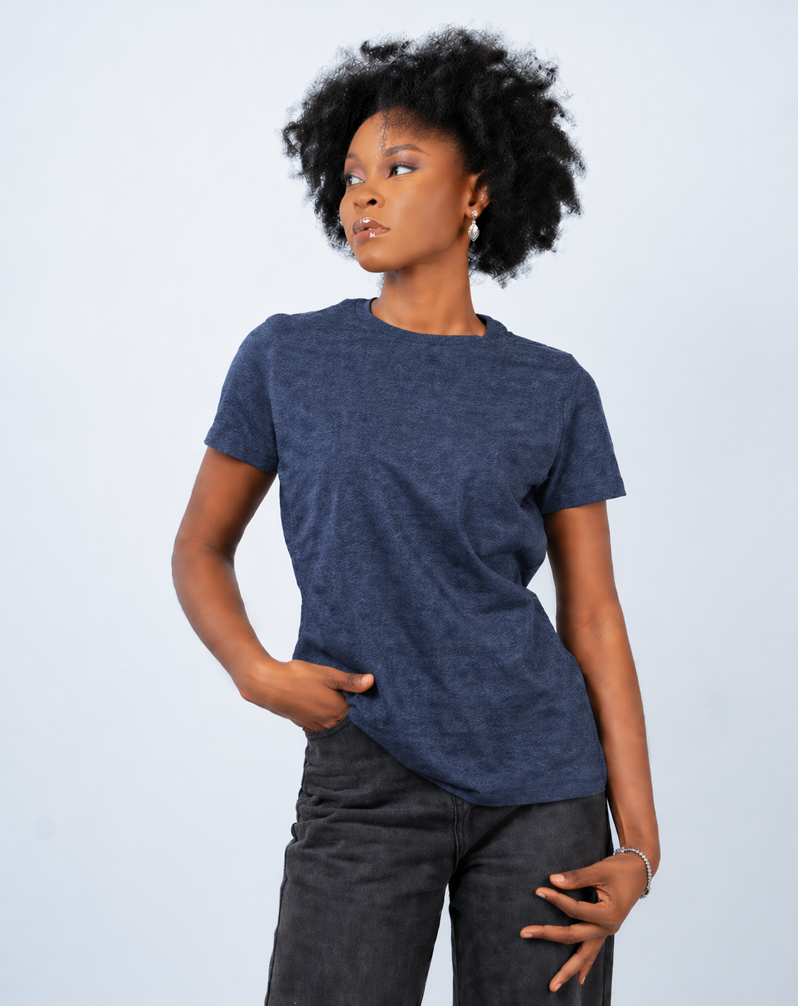 Person wearing a blue t-shirt and dark pants against a light gray background