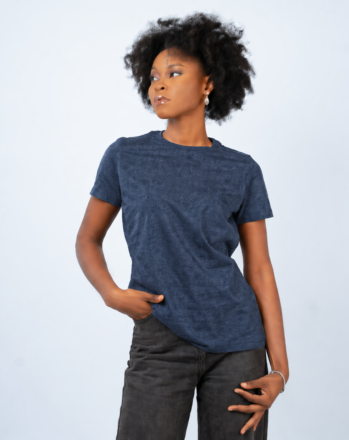 Person wearing a blue t-shirt and dark pants against a light gray background