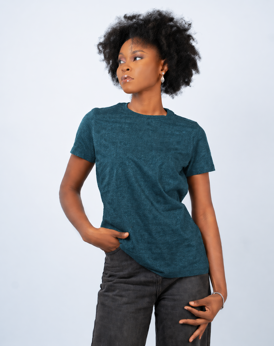 Person wearing a teal t-shirt and dark pants on a light gray background