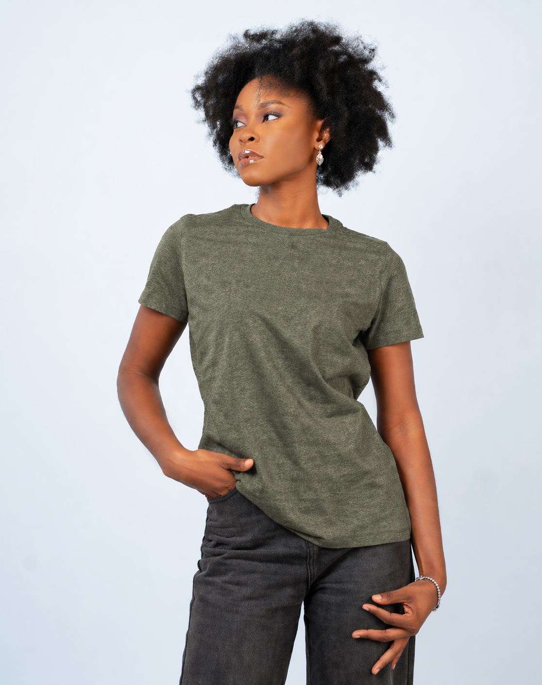 Person wearing a green t-shirt and dark pants against a light gray background